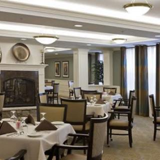 A well-lit dining area with neatly arranged tables and chairs, featuring elegant decor.