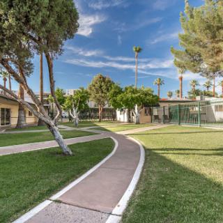 A serene pathway winding through a landscaped park, surrounded by lush greenery and trees.