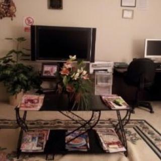 A cozy living room with a coffee table, television, and a computer desk.