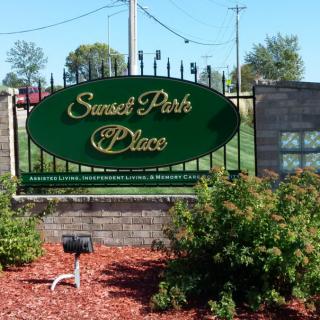 Entrance sign for Sunset Park Place surrounded by greenery.