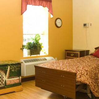 A cozy bedroom with a single bed, decorated with a floral bedspread, and sunlight streaming through the window.