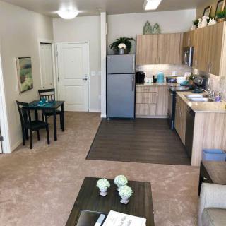 A modern apartment interior featuring a compact kitchen, dining table, and cozy living area.