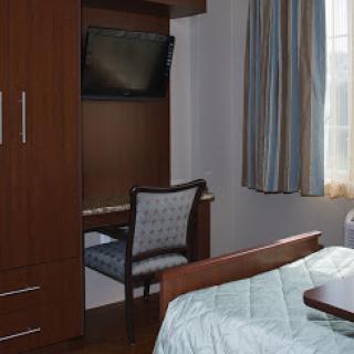 A cozy bedroom featuring a wooden bed, desk, and a television.