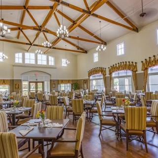 A spacious dining room with elegant chandeliers and neatly arranged tables and chairs.