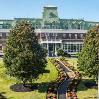 A historical building with a beautifully landscaped garden in front.