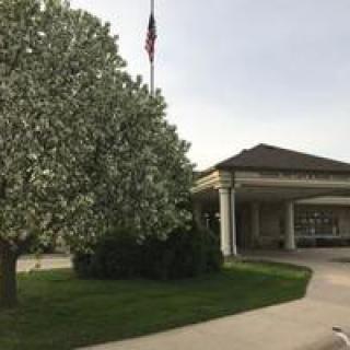 A building with a flowering tree and an American flag nearby.