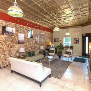A stylish living room interior featuring a white sofa, brick walls adorned with artwork, and modern ceiling lights.