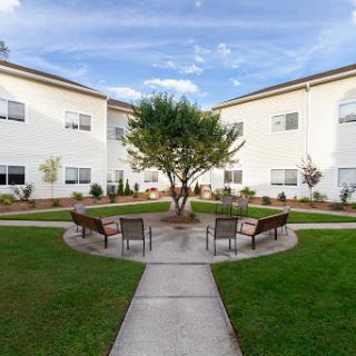 A serene courtyard featuring benches and a central tree, surrounded by residential buildings.