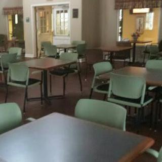 An empty cafeteria with green chairs and wooden tables.