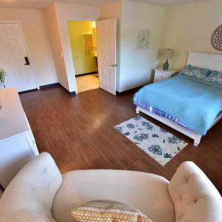 A cozy bedroom with wooden flooring, featuring a bed, armchair, and stylish decor.