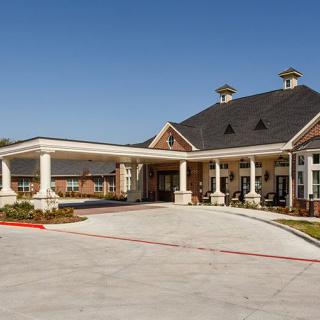 A large building with a covered entrance and columns set against a clear blue sky.