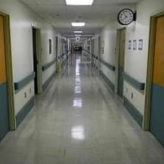An empty hospital corridor with fluorescent lighting.