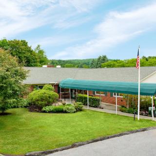 A well-maintained community center surrounded by lush greenery and a clear sky.
