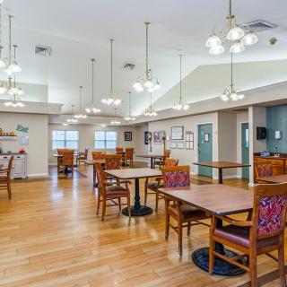 A spacious dining area with wooden floors and well-arranged tables and chairs.