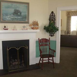 A cozy living room featuring a fireplace adorned with nautical decor and a wooden chair.