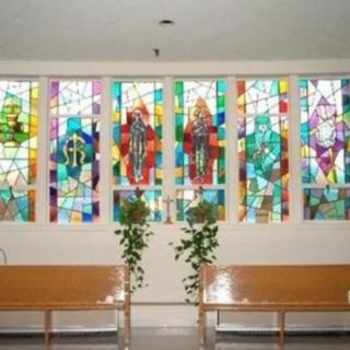 Interior view of a church featuring colorful stained glass windows and wooden benches.