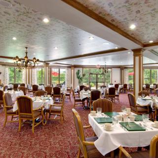 An elegant dining room with neatly arranged tables and chairs, adorned with chandeliers.