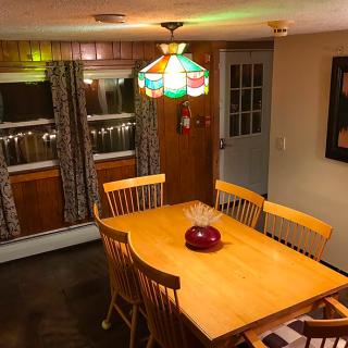 A cozy dining room featuring a wooden table with chairs and a colorful hanging lamp.