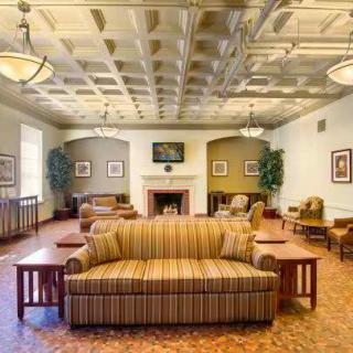 A spacious lounge area featuring a striped sofa, fireplace, and elegant ceiling lights.