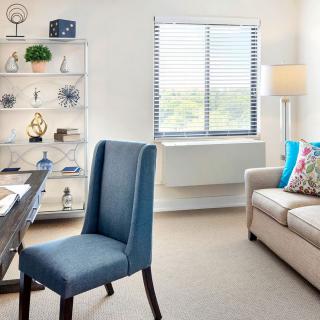 A modern and bright office space featuring a desk, chair, sofa, and decorative bookshelf.