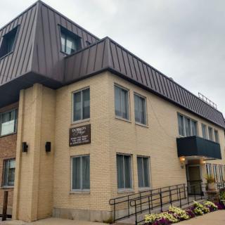 A modern office building with multiple windows and a sloped roof.