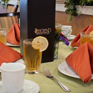 An elegantly set dining table with iced tea garnished with a lemon slice and neatly folded napkins.