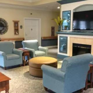 A cozy living room with armchairs, a fireplace, and a television.