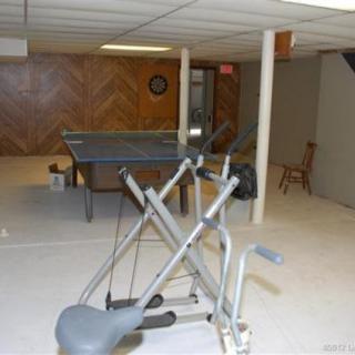 A home basement with exercise equipment and a ping pong table.