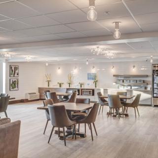 A modern cafe setting with neatly arranged tables and chairs, featuring stylish lighting and minimalist decor.
