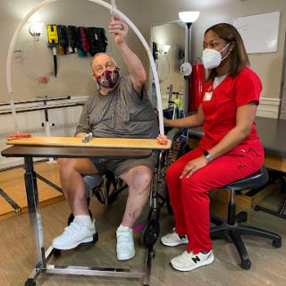 A healthcare professional assists a patient during a therapy session, focusing on rehabilitation exercises.