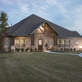 A beautiful brick house with a well-maintained lawn at dusk.