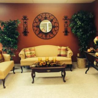 A cozy living room with elegant sofas, a coffee table, decorative plants, and a wall mirror.