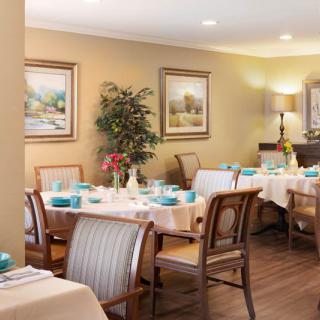 A cozy dining room with elegantly set tables, decorative artwork, and ambient lighting.