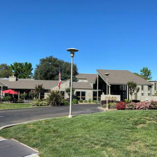 A scenic view of a residential building with a well-maintained lawn and clear blue sky.