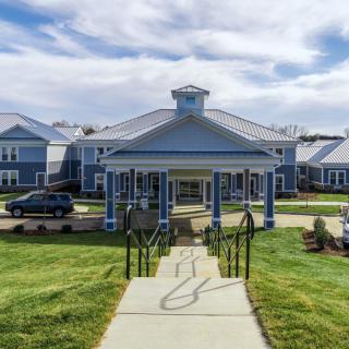 A building with a portico entrance and surrounding landscape.
