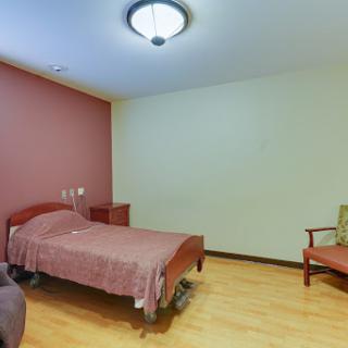 A simple and clean hospital room featuring a single bed and a chair.