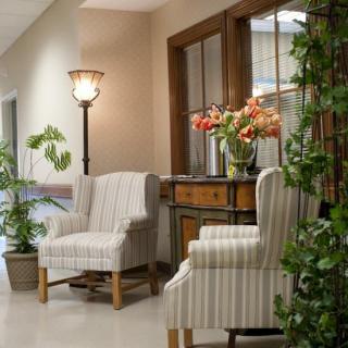 A cozy hallway with striped chairs, a decorative table adorned with flowers, and greenery for a welcoming atmosphere.