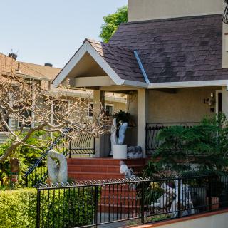 A charming house with a porch and lush greenery in the front yard.
