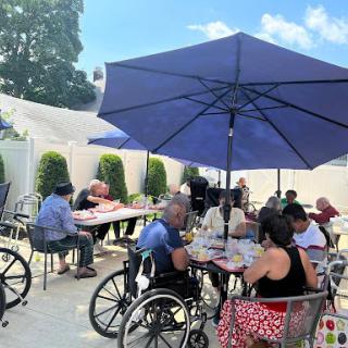 Seniors enjoying a meal together in a sunny outdoor setting.