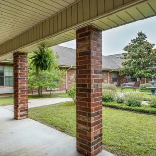 A serene courtyard featuring brick columns and lush greenery.