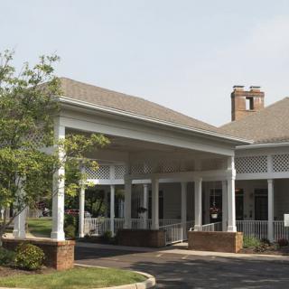 A building entrance with a covered canopy and surrounding greenery.