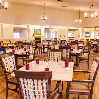 A spacious dining area with neatly arranged tables and chairs under warm lighting.