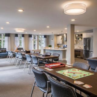A spacious recreation room with tables and chairs, featuring board games and ample natural light.