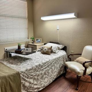 A cozy hospital room featuring a neatly made bed, a small table with decorative items, and comfortable seating.