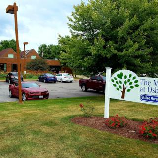 A view of The Woods at Osage showcasing the building, signage, and surrounding greenery.