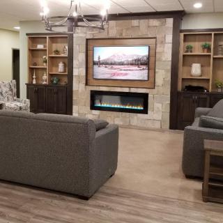 A modern living room with a cozy seating area, large television, and built-in fireplace.
