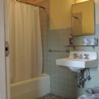 A vintage-style bathroom with a sink, bathtub, and tiled walls.