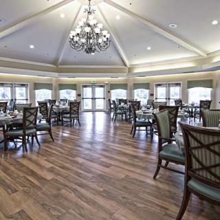 A spacious dining room with elegant furnishings and a central chandelier.