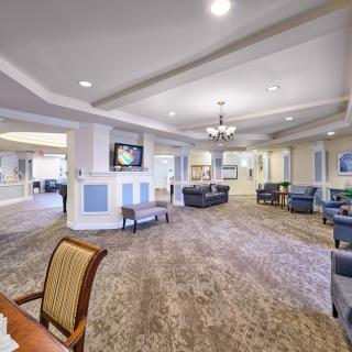 A spacious and elegantly designed lobby area featuring comfortable seating, a chandelier, and a television.