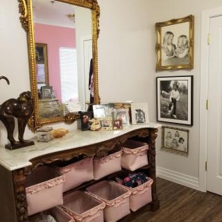 A beautifully decorated hallway with a large mirror above a vintage console table, featuring storage baskets and various decorative items.